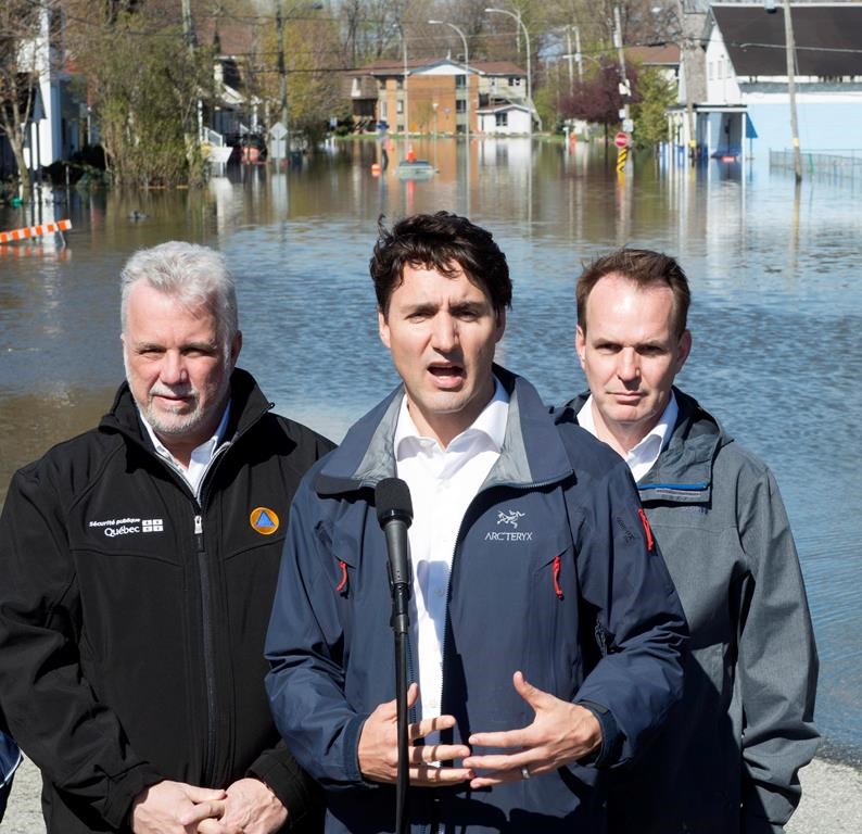 Quebec Premier Philippe Couillard and Gatineau MP Steve McKinnon look on as Canadian Prime Minister Justin Trudeau speaks to media following a tour of a flooded area of Gatineau, Que. Thursday May 11, 2017. Photo by the Canadian Press/Adrian Wyld